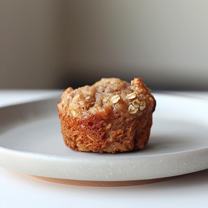 Close-up of oat apple muffins on a light grey ceramic plate with natural lighting.